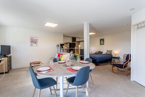 Een moderne woonkamer met een eethoek, een televisie en een bed.