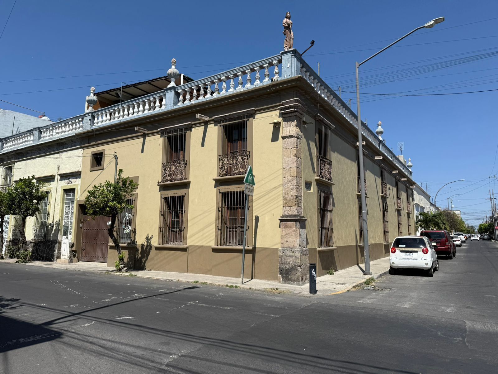 A building with a balcony, a streetlight, and parked cars.