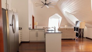 Una cocina moderna con una isla central, armarios blancos y un ventilador de techo.