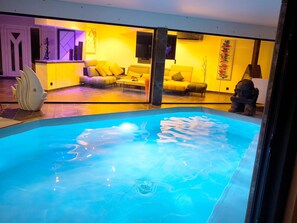 Ein Schwimmbad mit modernem Interieur, darunter eine Sitzecke und eine dekorative Fischskulptur.