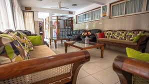 Egy hotel hall, amelyben kanapé, fa kávézóasztal és egy díszes váza található.