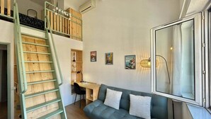 Habitación estilo loft con escaleras, un sofá, un escritorio y un ventanal grande.