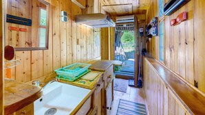 Ein Interieur einer Holzhütte mit einer Küchenzeile, darunter ein Spülbecken, ein Korb und ein Fenster.
