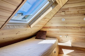 A wooden interior with a skylight, a bed, and a small table. - "Petit chalet chez Gaston" with Mountain View, Free Wi-Fi and Air Conditioning (Saint François Longchamp)