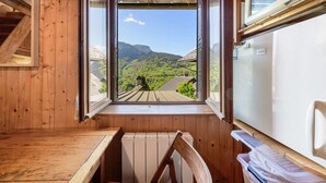 Eine Holzhütte mit Blick durch ein Fenster auf eine grüne Landschaft und Berge.