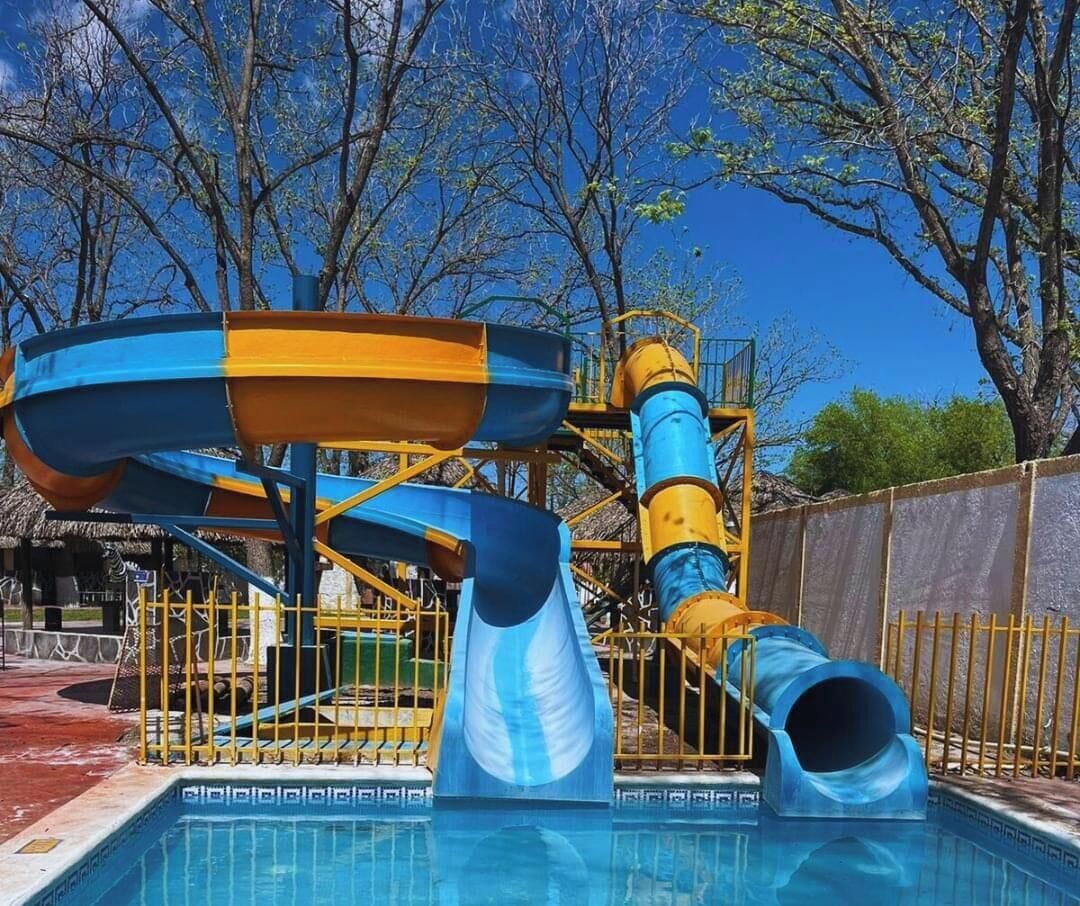 A water park with a pool, slides, and a play structure.
