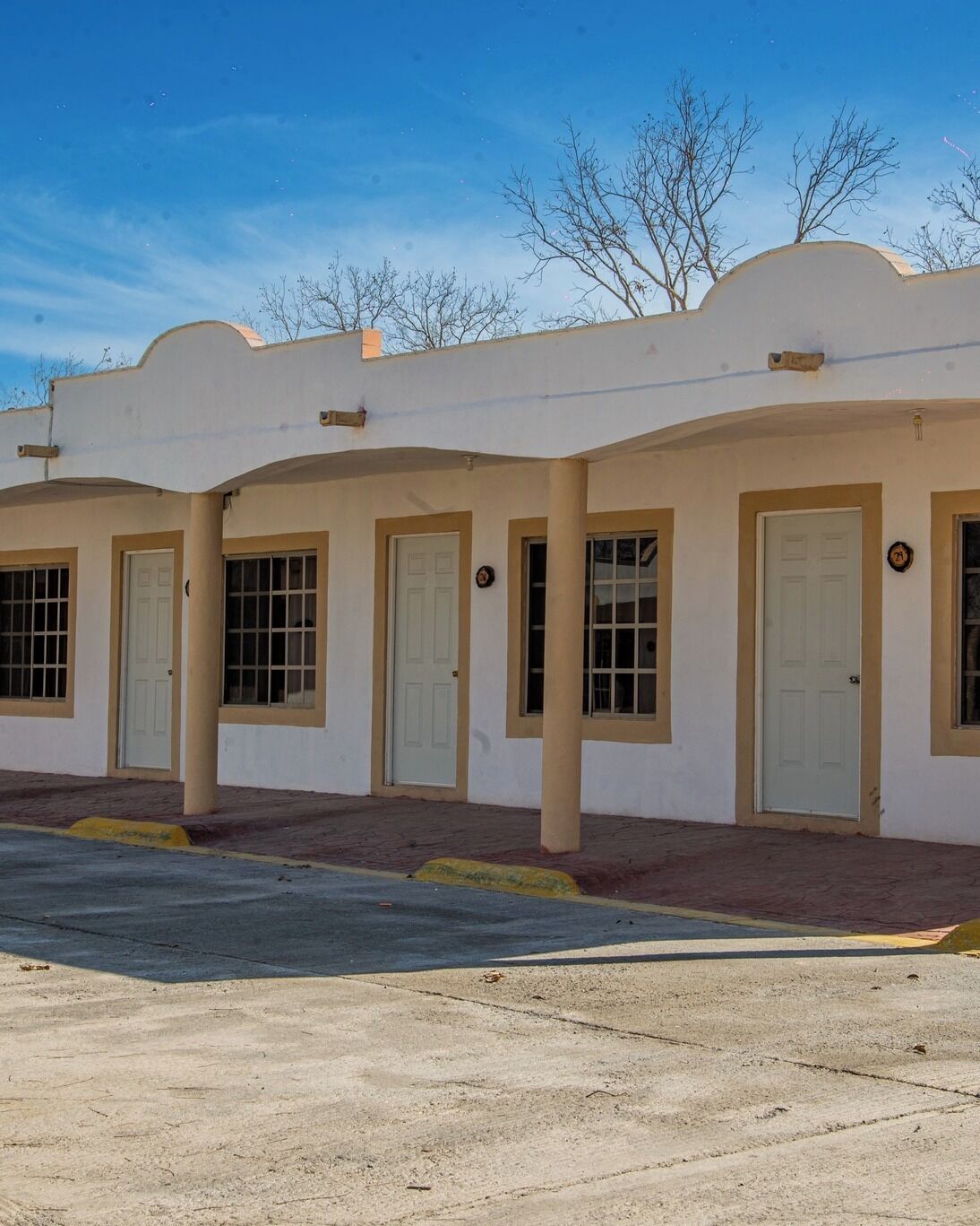 A row of single-story buildings with beige walls and white doors, featuring a simple architectural style.