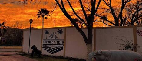 Señal para 'Pueblo Viejo Hotel & Parque acuatico' con un perro y un cerdo al frente.