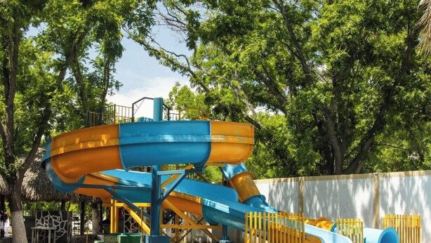 Un parc aquatique avec une piscine, des toboggans et des arbres.