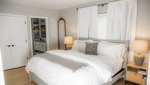 A bedroom with a bed, bedside tables, a wardrobe, and a mirror.