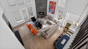 A modern living room with a fireplace, a large painting, and a staircase. - Worldcup Ready Luxury 6BR  Game Room  EV  Pets OK  Sleeps 24 (Irving)