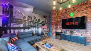 A living room with a sofa, coffee table, and a TV mounted on a brick wall. - Large apartment for 8 people, Sauna & SPA bath, travel around the world (Drusenheim)