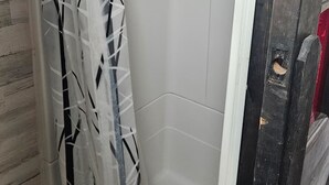 Eine Dusche mit einem gemusterten Vorhang, einer gefliesten Wand und einem Abfluss.