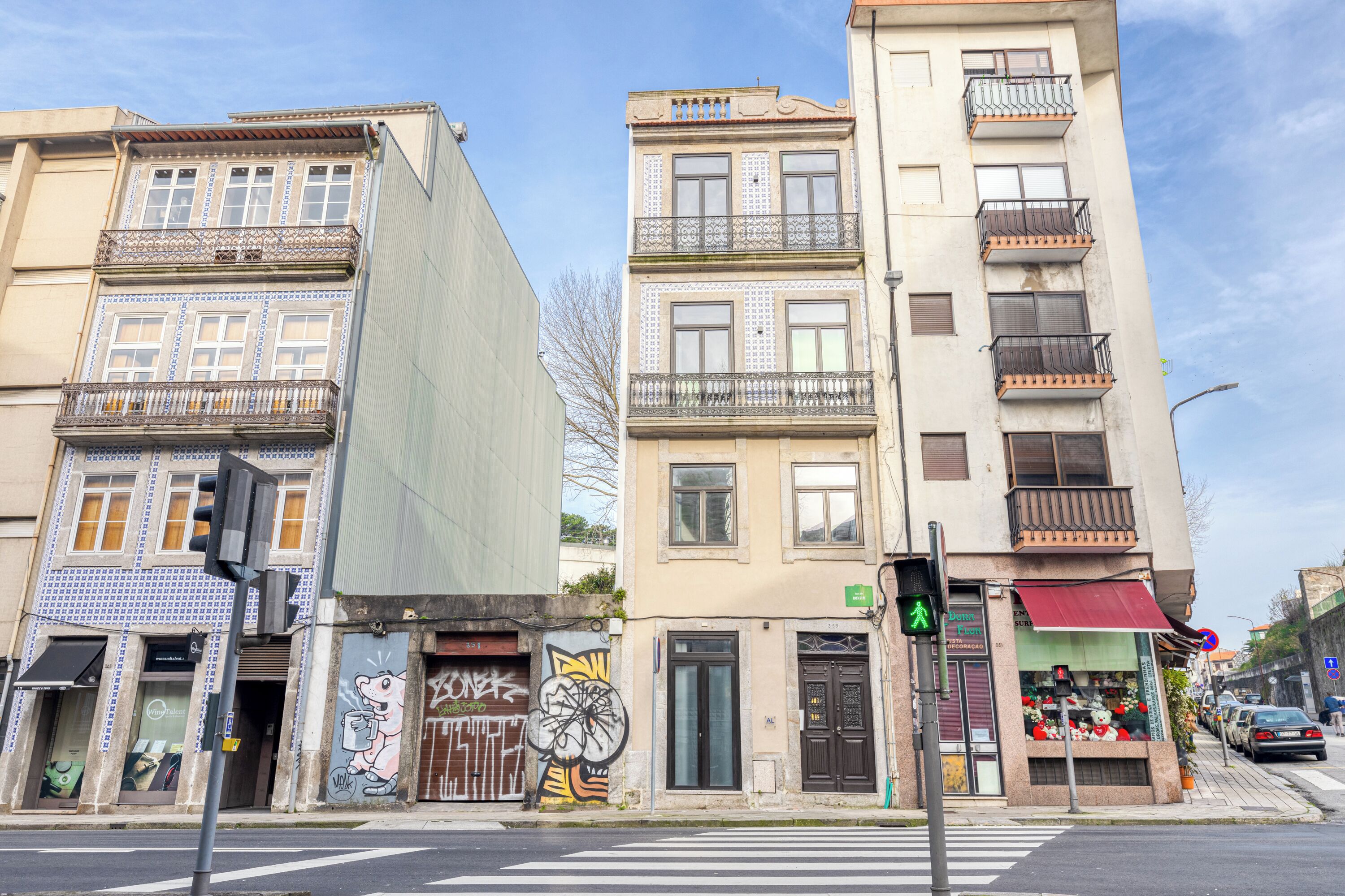 A street view with multi-story buildings, a pedestrian crossing, and a traffic light.