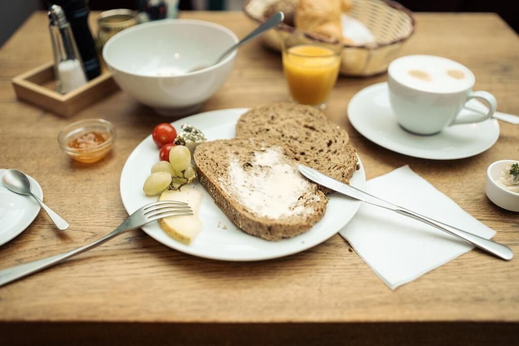 Une table en bois dressée pour le petit-déjeuner, avec du pain, des œufs et du jus.