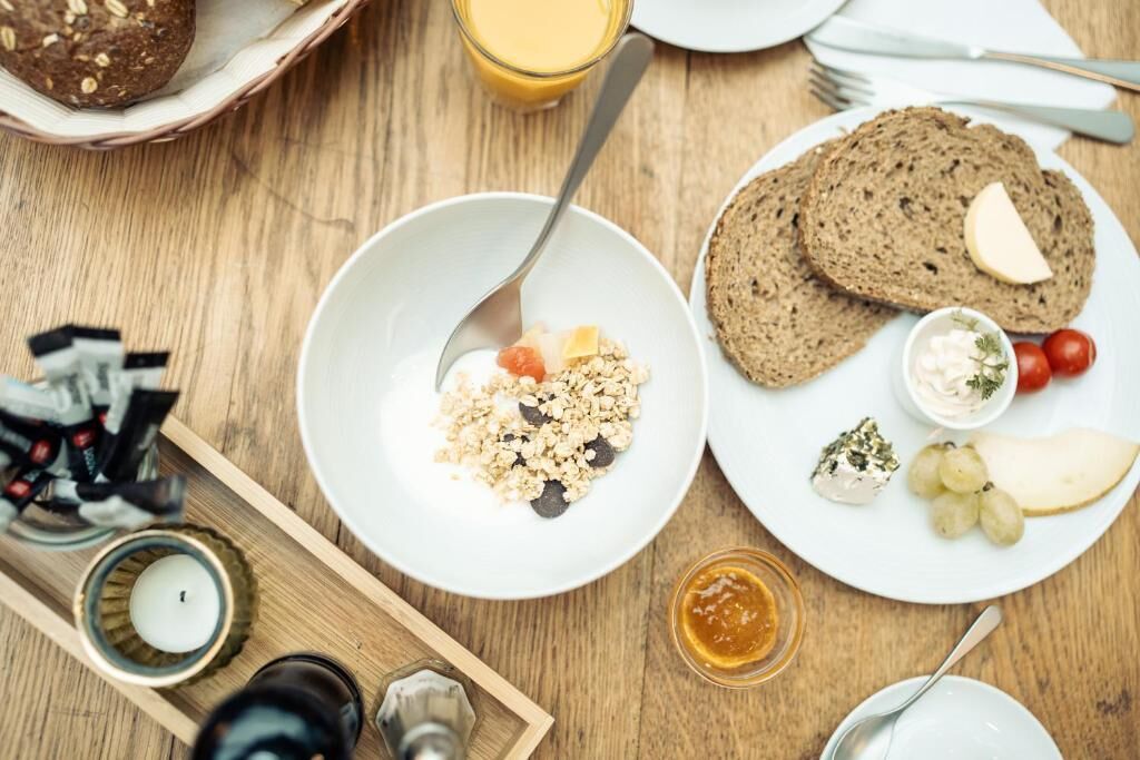 A breakfast setting with a plate of oatmeal, toast, cheese, and fruit, along with a glass of orange juice.