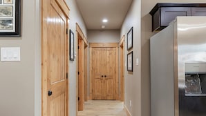 A hallway with wooden doors, a refrigerator, and framed pictures on the walls. - The Rainbow Trout Cabin, 3-bedroom/2 bath , Dog-friendly, Firepit, Secluded (Cassville)