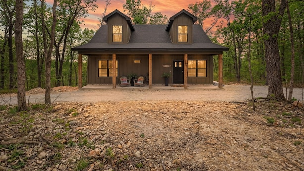 A two-story house with a porch, large windows, and a door. - The Rainbow Trout Cabin, 3-bedroom/2 bath , Dog-friendly, Firepit, Secluded (Cassville)