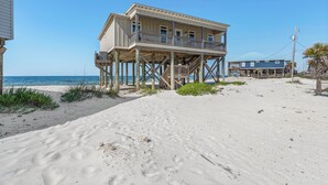 Une maison située en bord de mer, dotée d’un balcon, d’une terrasse en bois et offrant une vue dégagée sur l’océan.