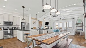Une cuisine moderne avec des meubles blancs, un îlot central en bois et des luminaires suspendus.