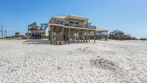 Une maison située en bord de mer, dotée d’un balcon, d’une terrasse en bois et de plusieurs niveaux.
