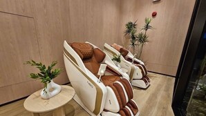 A massage room with two massage chairs, a small table with a plant, and a potted plant on the wall. - Room-dcondo Reef Kathu Patong (Kathu)