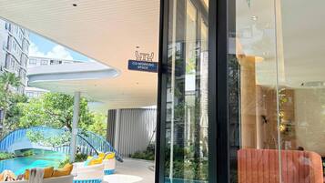 A modern hotel with a glass entrance, a pool area with lounge chairs, and a sign indicating a co-working space.
