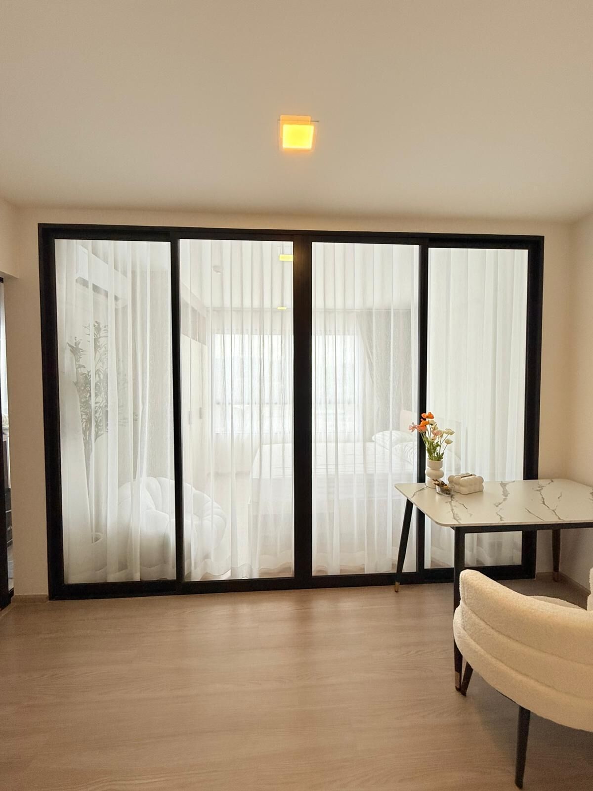 A room with a sliding glass door, a small table with a vase, and a chair.