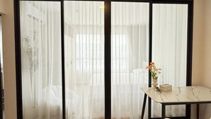 A room with a sliding glass door, a small table with a vase, and a chair. - Room-dcondo Reef Kathu Patong (Kathu)