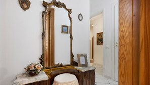 Ein Zimmer mit einem Holznächtigungsschrank, einem großen Spiegel, einem gerahmten Zertifikat und einer Tür zu einem anderen Raum.