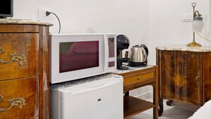 Eine kompakte Küchenzeile mit Mikrowelle, Kaffeemaschine und kleinem Kühlschrank.