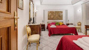 Ein Hotelzimmer mit zwei Betten, einem Holzkapständer, einem Sessel, einem großen Spiegel und einem Bild an der Wand.