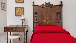 Ein Schlafzimmer mit einem hölzernen Bett, einem Nachttisch, einer Lampe und zwei gerahmten Bildern an der Wand.