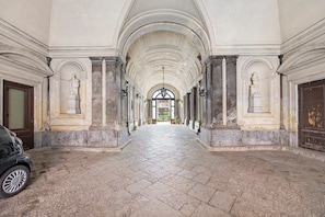 A corridor with a stone floor, arched ceiling, and statues on either side. - Apartment 'Al Palazzo Del Principe Al Massimo' with Wi-Fi and Air Conditioning (Palermo)