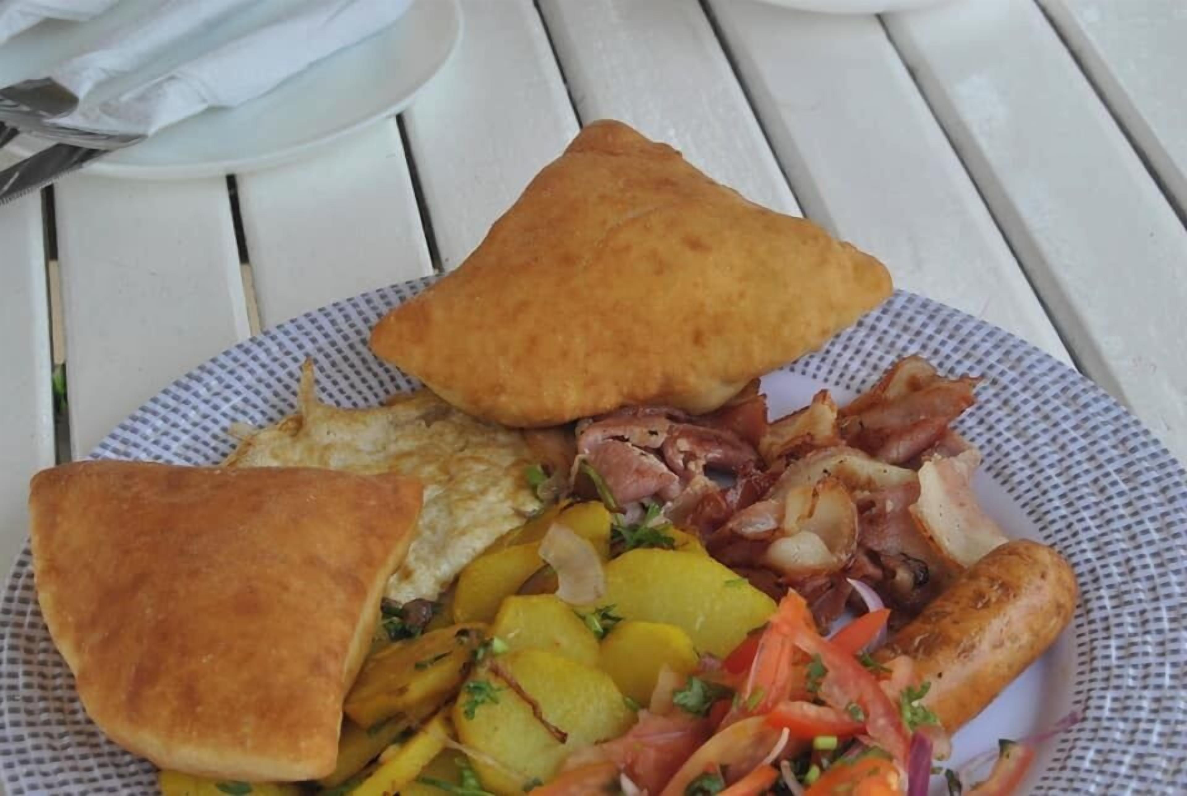 A plate of food with toast, eggs, bacon, potatoes, and vegetables.