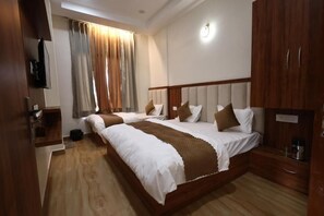 A hotel room with a large bed, a bedside table, a wardrobe, and a window with curtains. - Hotel Om Divine (Vrindavan)