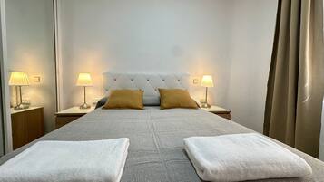 Habitación de hotel con una cama grande, dos mesitas de noche con lámparas y un cabecero con diseño de diamantes.