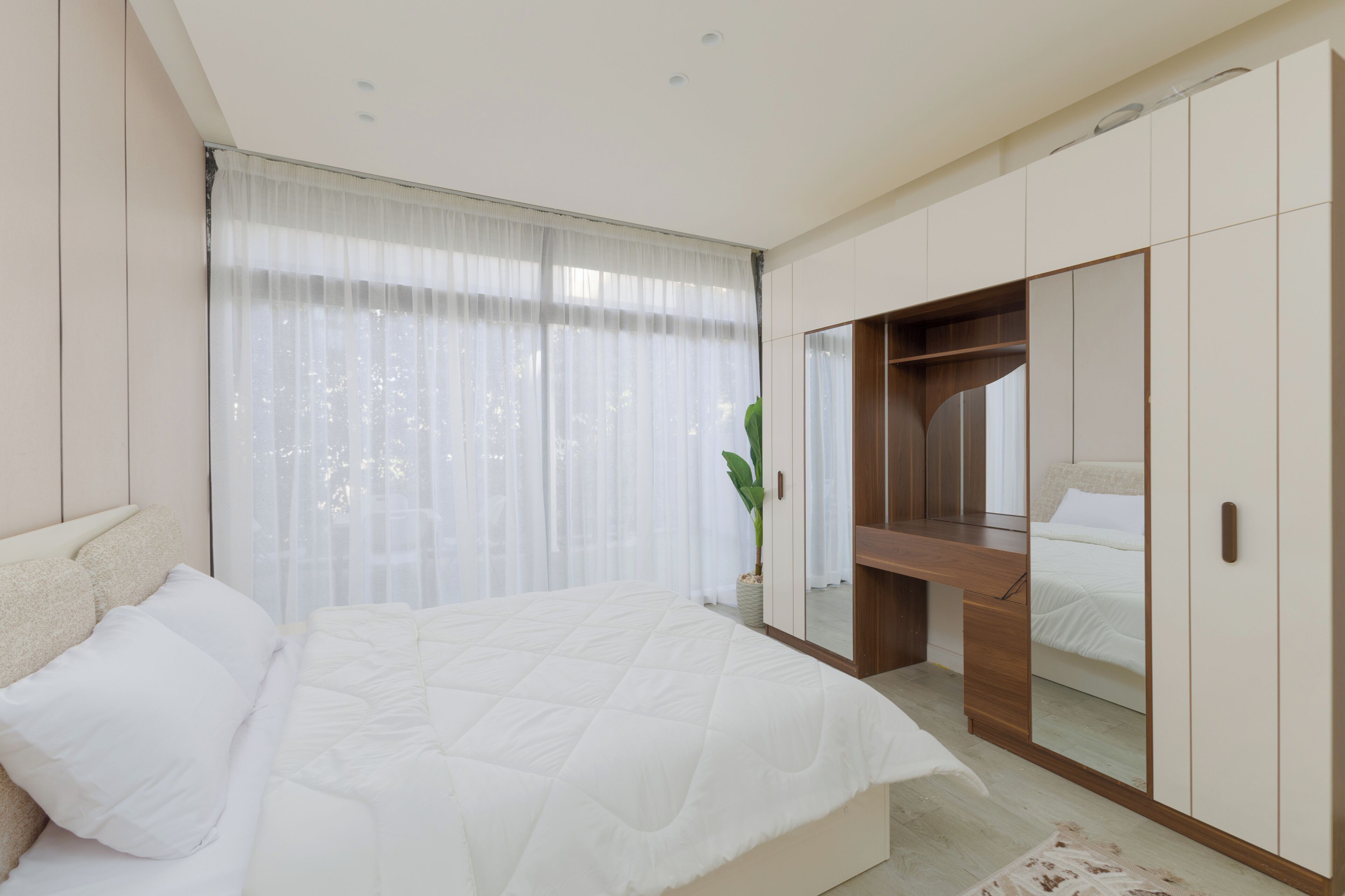 A bedroom with a bed, a desk, and a wardrobe.