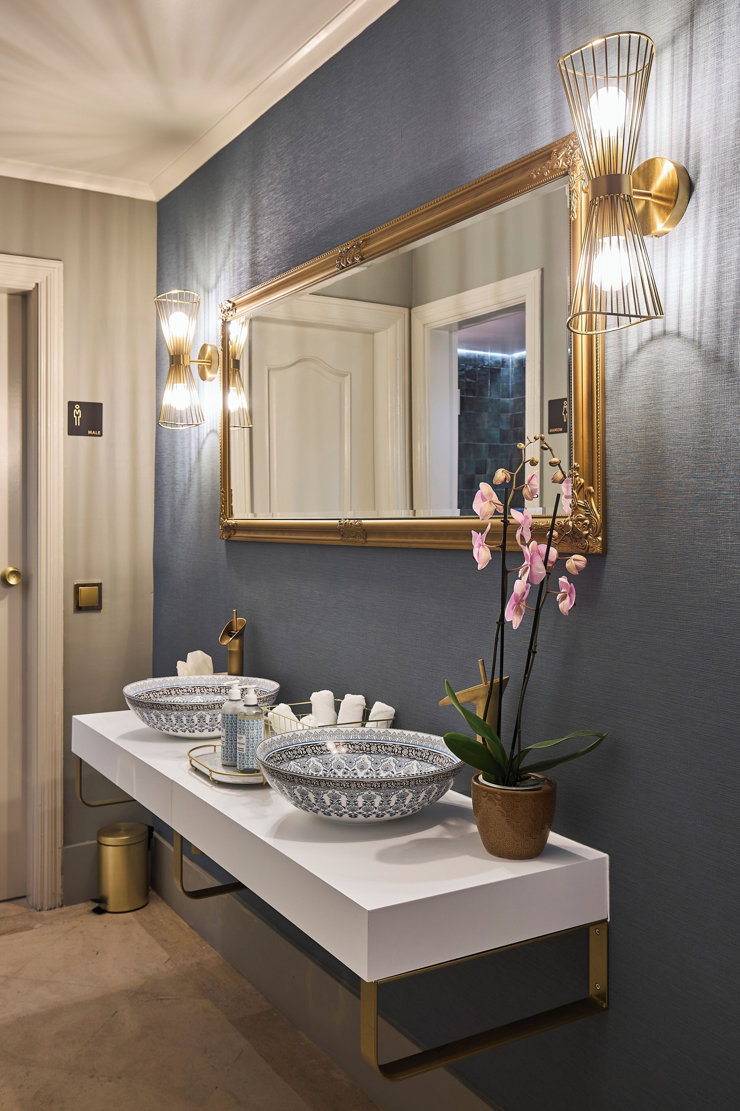 A bathroom with a double sink, a large mirror, and a wall-mounted light fixture.