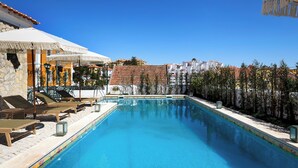 A swimming pool with lounge chairs and umbrellas, surrounded by buildings. - Estoril Boutique Hotel - Adults only (Cascais)