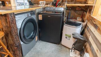 Een kleine keuken met een wasmachine, een compacte koelkast en een klein oven.