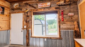 A rustic interior with a wooden door, a window with a view, a sign reading 'PERRY'S RESORT', and a rustic wall decor. - Cozy 1BR Lakefront Retreat on Rice Lake – Sleeps 6 | Fishing & Snowmobile Paradise (Spooner)