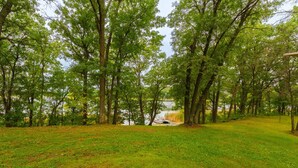 A grassy area with trees and a body of water in the background. - Cozy 1BR Lakefront Retreat on Rice Lake – Sleeps 6 | Fishing & Snowmobile Paradise (Spooner)