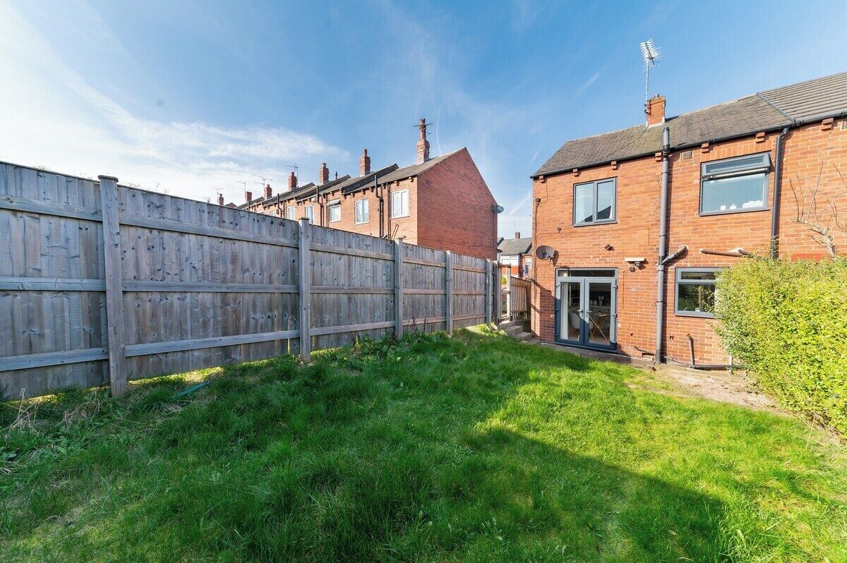 A residential area with a wooden fence, a brick house, and a clear sky.