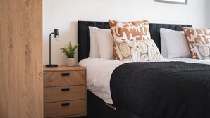 Ein Schlafzimmer mit Bett, Nachttisch, Lampe und einer kleinen Pflanze.