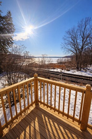 Una terraza de madera con vistas a un paisaje nevado y una vía de tren.