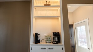 Una cocina con repisa empotrada sobre un armario blanco, que contiene una cafetera, un vaso y un objeto decorativo.