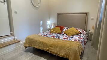 Une chambre à coucher comprenant un lit, une table de chevet, une lampe, un luminaire fixé au mur, une porte et une fenêtre avec des rideaux.