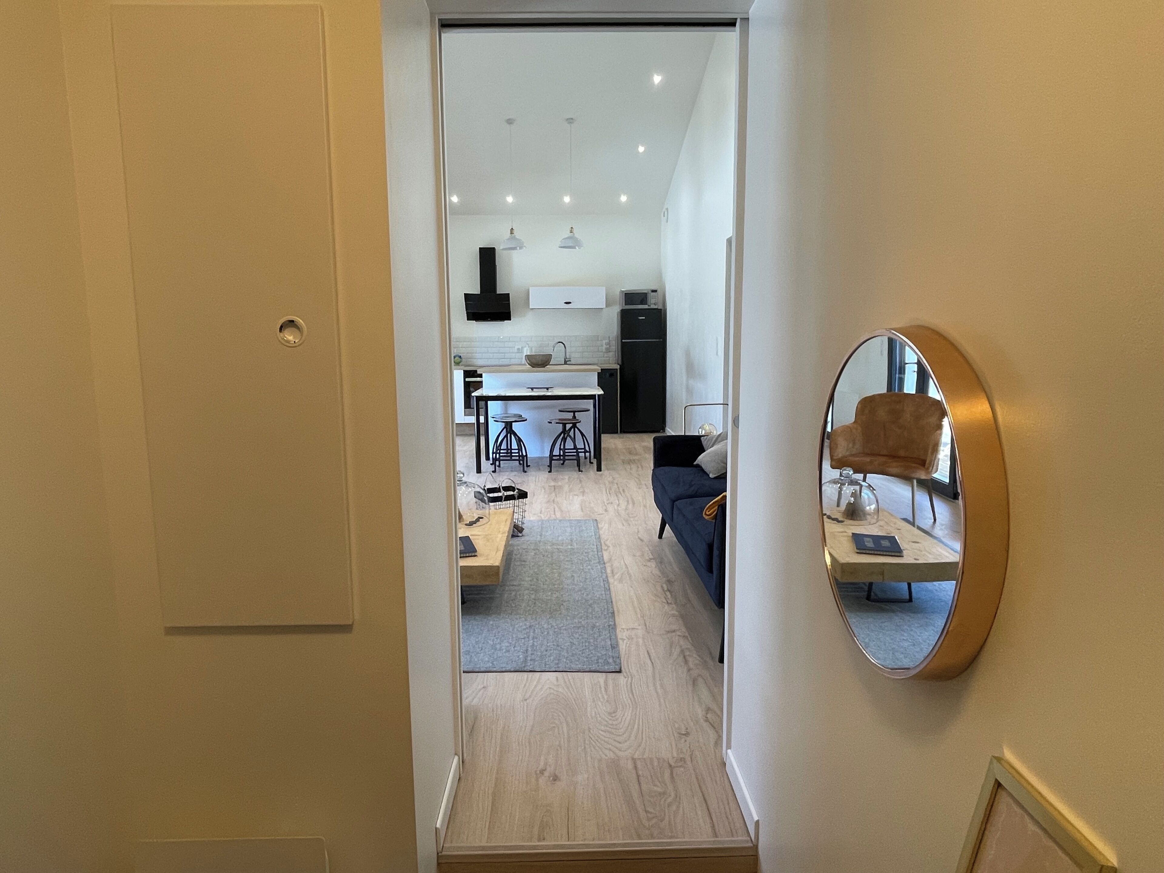 Un ambiente moderno con cucina, zona pranzo e uno specchio a parete.