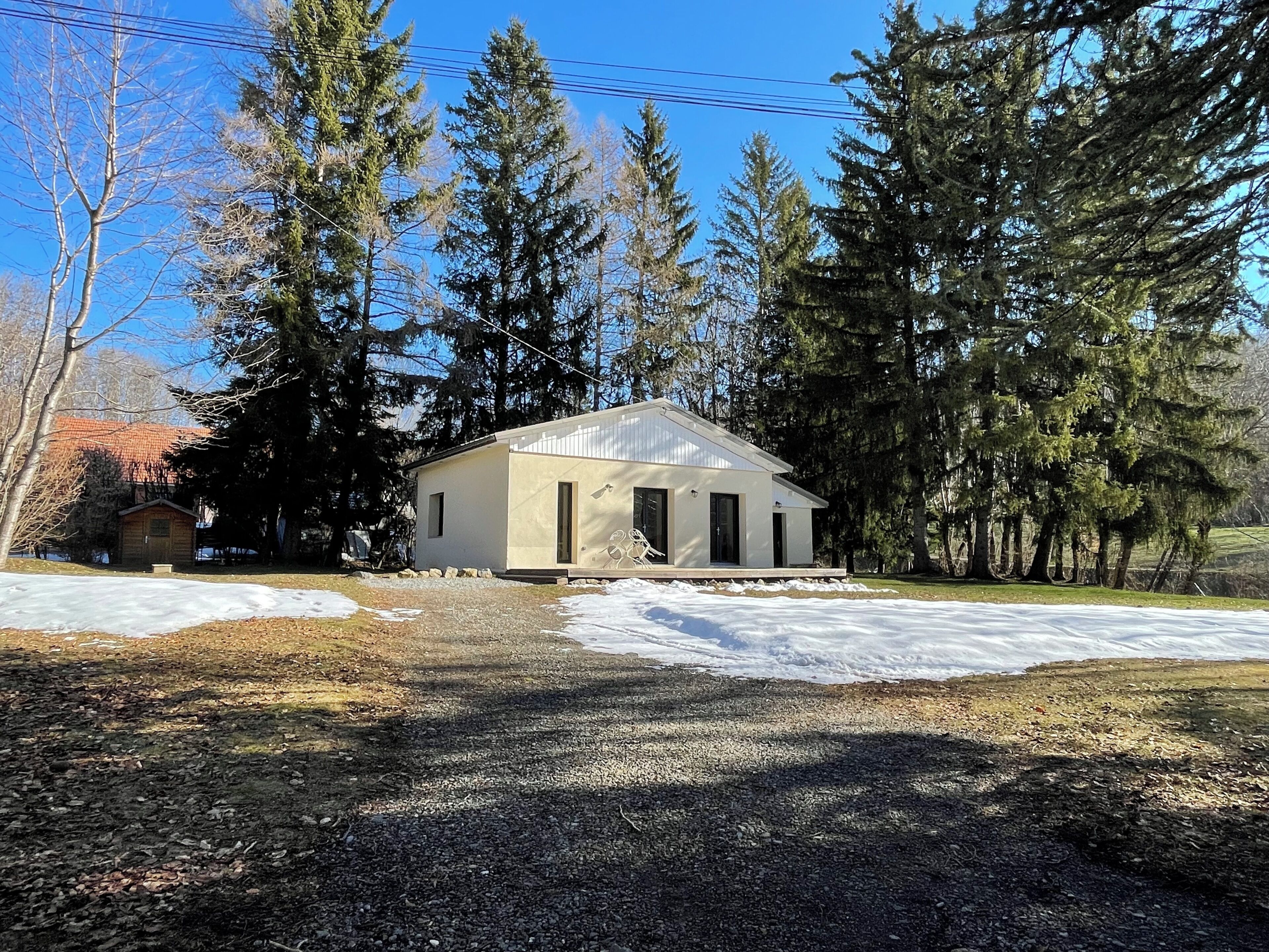 A single-story building with a gabled roof, surrounded by trees and a snow-covered ground.